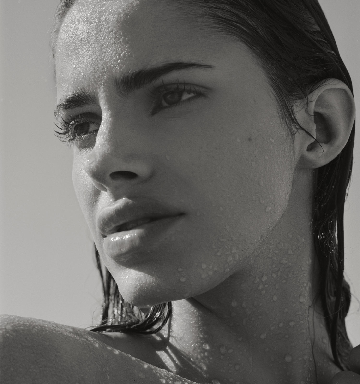 Black and white photo of female model Carmin Valencia on a New Jersey beach, her hair is wet, water droplets on her face and body. Photographed by New York photographer Maria Bruun. Mamiya RZ67 camera and Ilford film. "High Tide" Fashion editorial for Nasty Magazine.